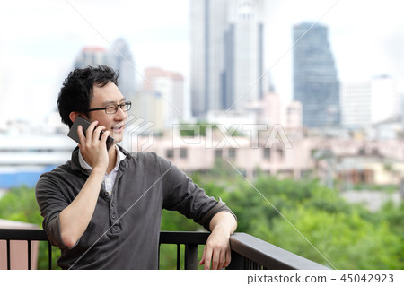 Asian man talking on smartphone smiling Asian man talking on smartphone smiling 45042923