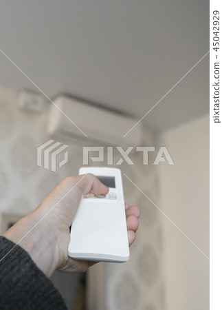 Hand with remote control directed on the conditioner on the wall. Man's hand using remote control Hand with remote control directed on the conditioner on the wall. Man's hand using remote control 45042929