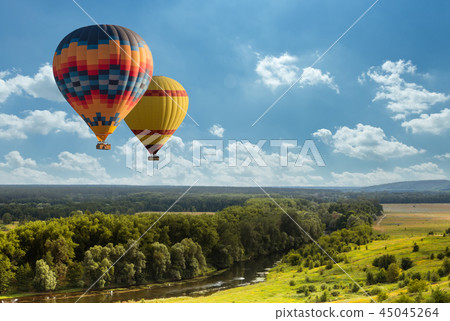 Colorful hot air balloon flying over green field 45045264