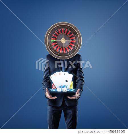 A businessman with a casino roulette instead of his head stands and offers cards, dice and casino A businessman with a casino roulette instead of his head stands and offers cards, dice and casino 45045605