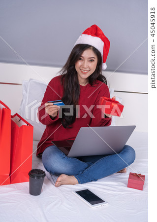 happy woman shopping online for Christmas gift with computer lap 45045918