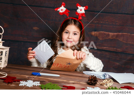 Child writes letter to Santa Claus . Funny girl in Santa hat writes letter to Santa 45046044