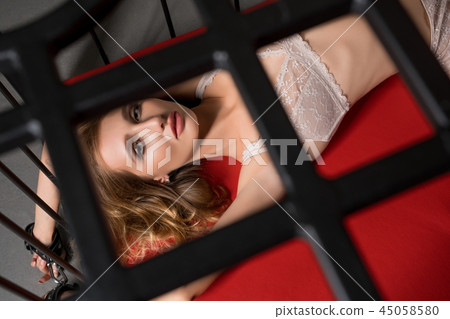 Woman in lingerie with handcuffs in metal cage shot 45058580