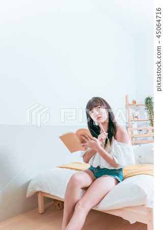 甜美可愛亞洲女孩坐在床上在拿筆看書思考 45064716
