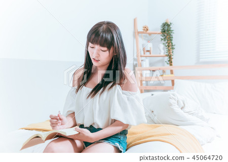 Sweet cute asian girl sitting on bed laughing and happy while reading a pen 45064720