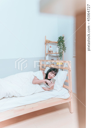 甜美可愛亞洲女孩躺在床上笑著開心拿著手機自拍視訊聊天 45064727