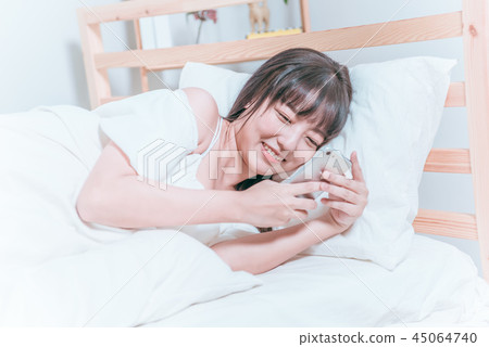 甜美可愛亞洲女孩躺在床上笑著開心拿著手機自拍視訊聊天 45064740