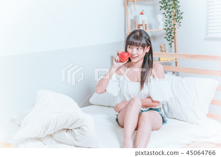 甜美可愛亞洲女孩坐在床上開心微笑拿著蘋果準備吃 45064766
