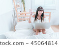 Sweet cute asian girl sitting on the bed and laughing happy using laptop computer video chat website 45064814
