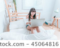 Sweet cute asian girl sitting on the bed and laughing happy using laptop computer video chat website 45064816