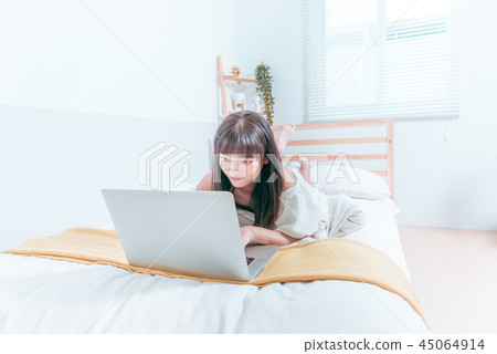 Sweet cute asian girl happy laughing in bed using laptop computer video chat website 45064914