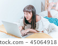 Sweet cute asian girl happy laughing in bed using laptop computer video chat website 45064918