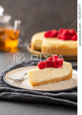 Slice of New York Cheesecake with raspberries on a dark background. 45065777