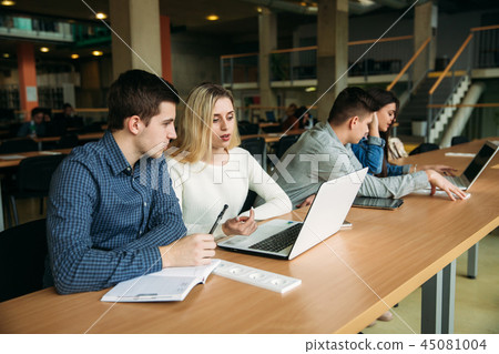 Group of college students studying in the school library, a girl and a boy are using a laptop and Group of college students studying in the school library, a girl and a boy are using a laptop and 45081004