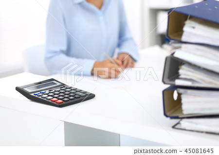 Calculator and binders with papers are waiting to be processed by business woman or bookkeeper back 45081645