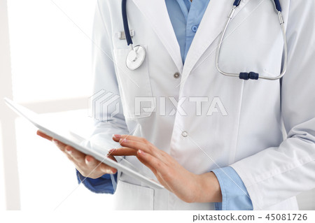 Woman doctor using tablet computer while standing straight in hospital closeup. Healthcare 45081726