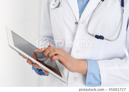 Woman doctor using tablet computer while standing straight in hospital closeup. Healthcare 45081727