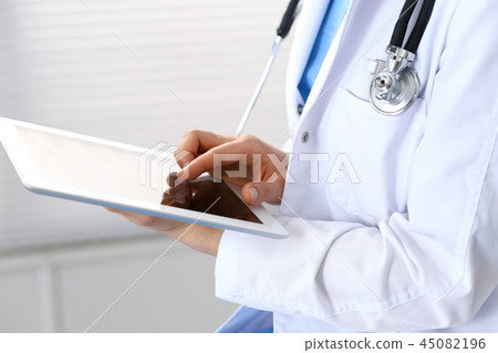 Woman doctor using white tablet computer while working in hospital, close-up 45082196