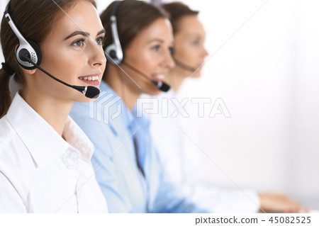 Group of callcenter operators at work. Focus at beautiful business woman in headset Group of callcenter operators at work. Focus at beautiful business woman in headset 45082525