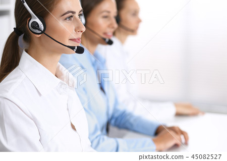 Group of callcenter operators at work. Focus at beautiful business woman in headset Group of callcenter operators at work. Focus at beautiful business woman in headset 45082527