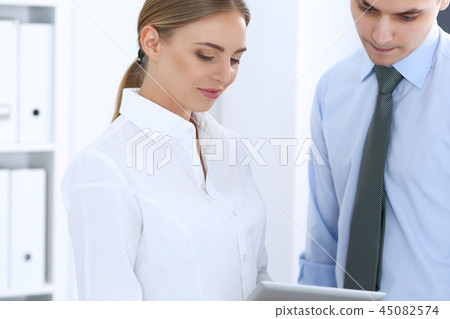 Beautiful blonde business woman using tablet or touch-pad with her male colleague or partner in Beautiful blonde business woman using tablet or touch-pad with her male colleague or partner in 45082574
