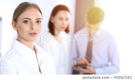 Beautiful blonde businesswoman standing straight in a brightly lit office at the background of 45082583