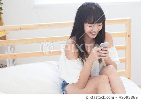 在床上使用手機的美女 在床上使用手機的美女 45095869