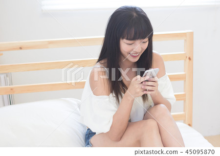 Beautiful woman using mobile phone in bed 45095870