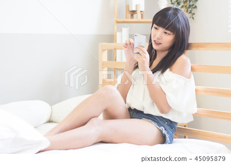 在床上使用手機的美女 在床上使用手機的美女 45095879