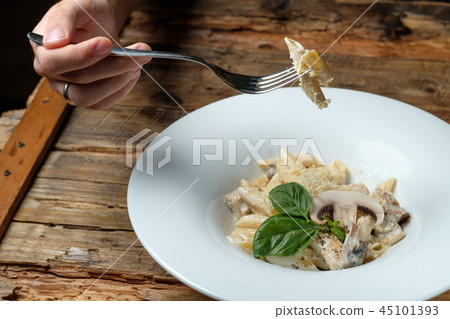 Man's hand holding a fork with pasta 45101393
