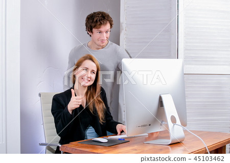 Portrait of young successful woman and man at office. They look at the display approvingly. Black Portrait of young successful woman and man at office. They look at the display approvingly. Black 45103462