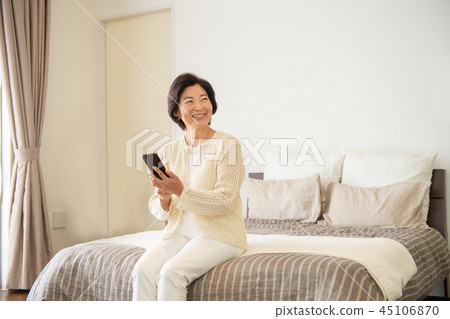 Senior woman smartphone bedroom lifestyle image 45106870
