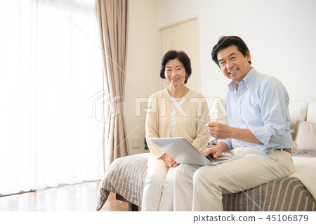 Senior couple personal computer bedroom lifestyle image 45106879
