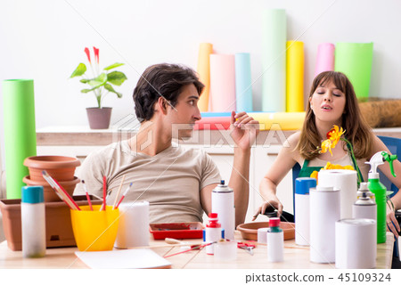 Couple decorating pots in workshop during class Couple decorating pots in workshop during class 45109324
