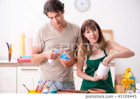 Couple decorating pots in workshop during class Couple decorating pots in workshop during class 45109445