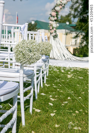 Summer outdoor wedding ceremony decoration. White chairs decorated with gypsophila balls on the 45109465