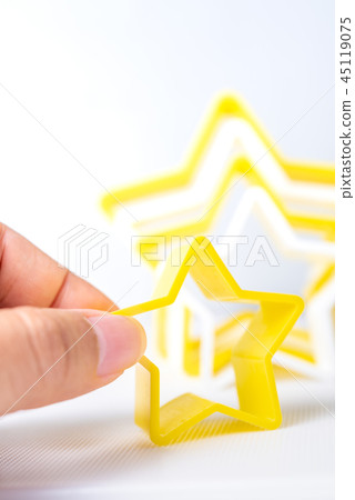 Hand holding star shaped pastry cutter on table Hand holding star shaped pastry cutter on table 45119075