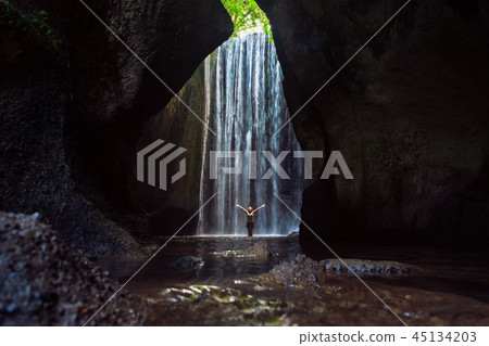Woman stand under cave waterfall 45134203