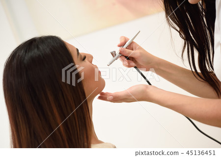 Make-up artist using aerograph making an airbrush make up 45136451