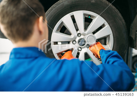 Mechanic unscrews the wheel, tire service Mechanic unscrews the wheel, tire service 45139163