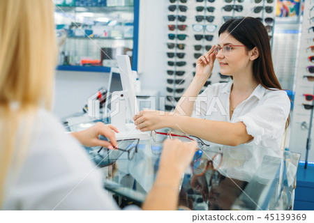 Female optician and consumer chooses glasses frame Female optician and consumer chooses glasses frame 45139369