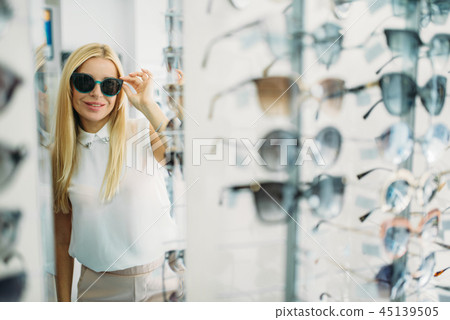 Female customer tries on sunglasses, optics store Female customer tries on sunglasses, optics store 45139505