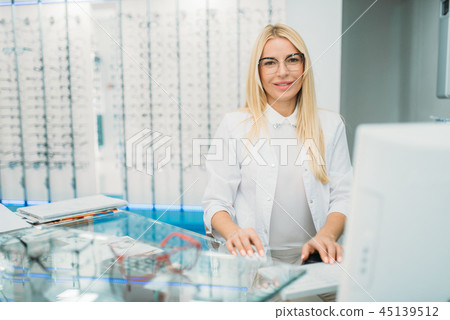 Female optician sitting at table in optics store 45139512