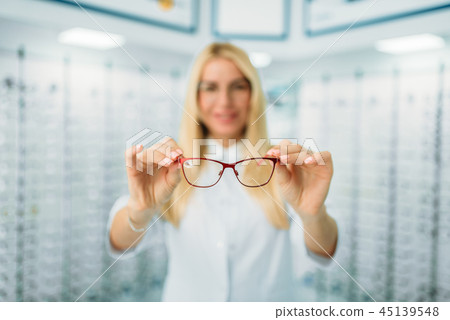 Female optician shows glasses in optics store 45139548