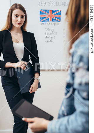 Two female students talking in classroom. College, English language school. Two female students talking in classroom. College, English language school. 45146433