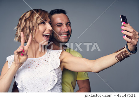 Happy couple in studio laughing over grey 45147521