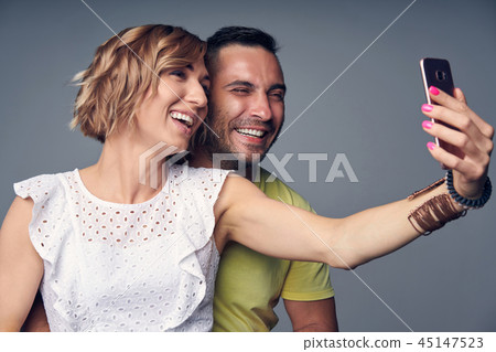Happy couple in studio laughing over grey 45147523