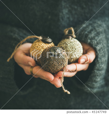 Woman holding golden and silver balls in hands, square crop 45147749