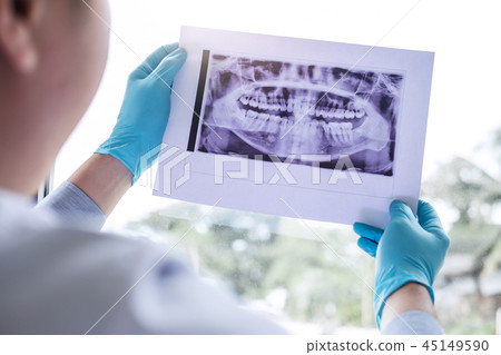 Image of male doctor or dentist holding and looking at dental x- 45149590