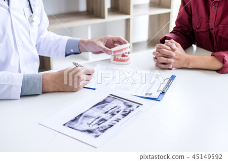 Male doctor or dentist writing report working with tooth x-ray f 45149592